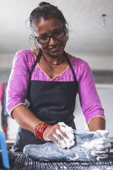 SHUS.dk håndværker i Nepal der filter en denimblå uldhjemmesko med sæbeskum under produktionen