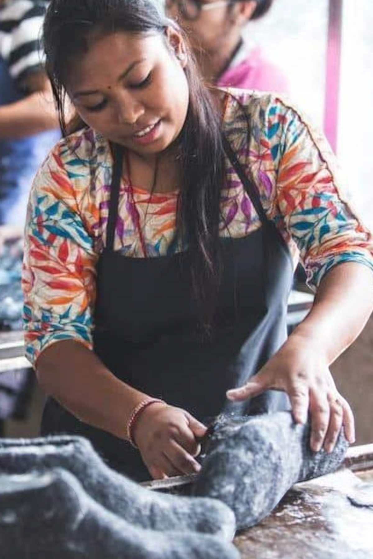 SHUS.dk håndværker i Nepal der omhyggeligt former en denimfarvet uldhjemmesko af 100% ren New Zealandsk uld