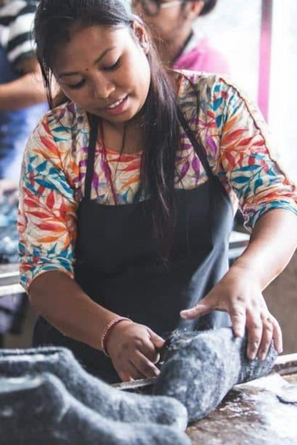 SHUS.dk håndværker i Nepal der omhyggeligt former en denimfarvet uldhjemmesko af 100% ren New Zealandsk uld