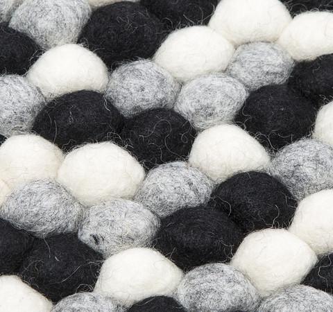 Sort og hvidt håndlavet kugletæppe af 100% ren uld tilføjer hygge og stil. Blødt uld materiale og enestående design. Perfekt til at skabe en varm atmosfære i dit hjem.